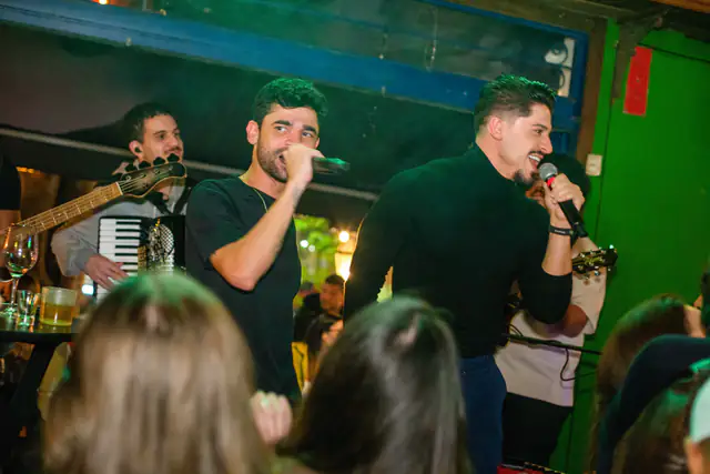 Cantores da Acustify se apresentando ao vivo em um bar lotado