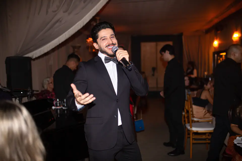 Cantor da Acustify se apresentando ao vivo em restaurante, entre as mesas dos clientes